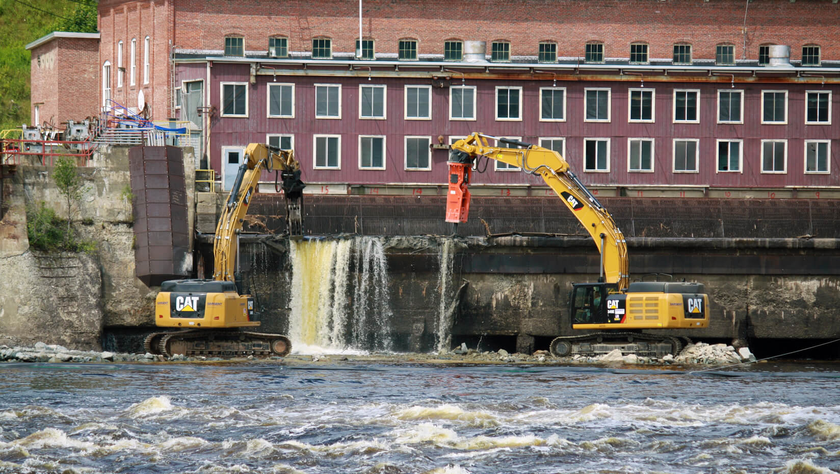 heavy equipment deconstructing a dam