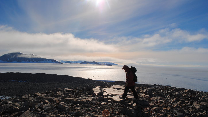 Brenda Hall hiking along a coastline during a research expedition.