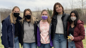 Five students from the University of Maine chapter of Kappa Omicron Nu stand outside together wearing coats and face masks.